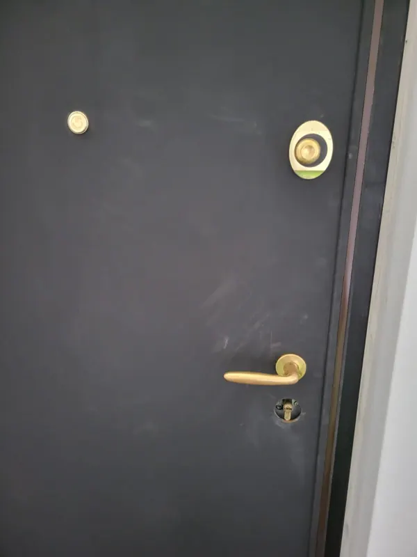 Porta blindata scura con defender, spioncino e cilindro di sicurezza